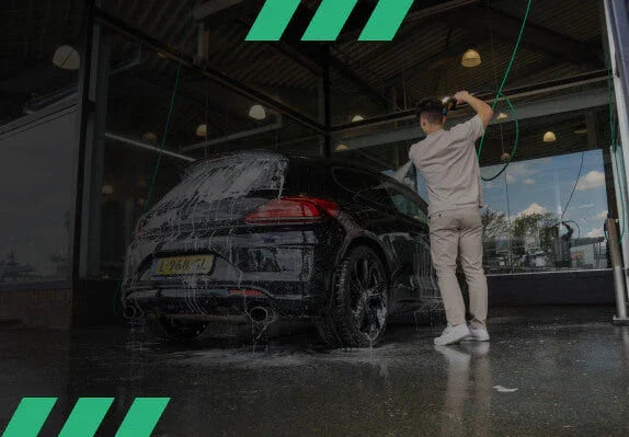 Detailrs hogedruk autowasapparaat gebruikt door man in beige kleding voor zwarte auto wassen bij zelfbedieningswasstraat