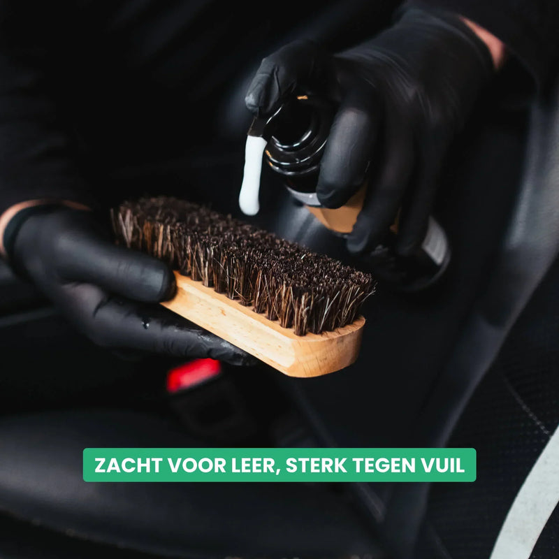 Detailrs lederen reiniger en houten borstel met zwarte handschoenen in autointerieur