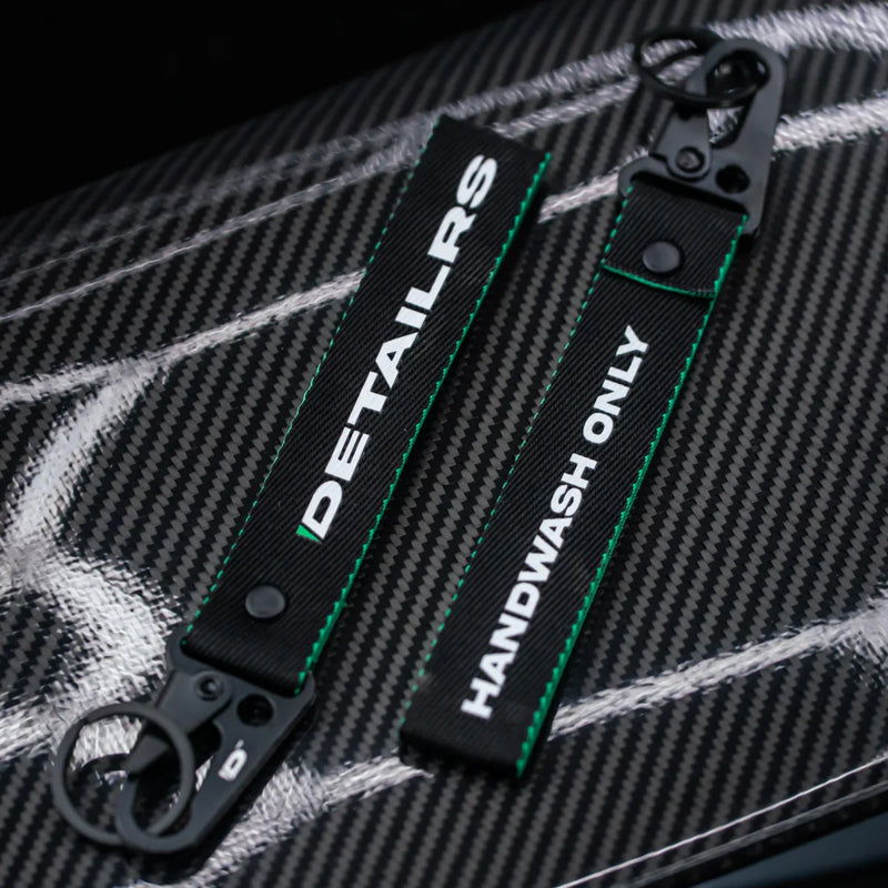 Detailrs sleutelhanger met tekst 'DETAILRS' en 'HANDWASH ONLY' op zwarte keycords met groene stiksels