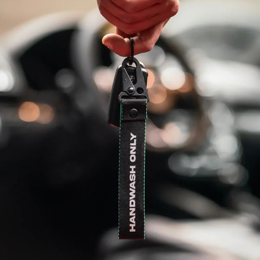 Detailrs sleutelhanger Handwash Only zwart textiel met metalen haak in hand voor autostuur
