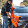 Detailrs microvezel drooghandschoen in gebruik, man droogt zwarte auto met oranje doek