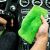 Detailrs interieurreiniger wordt gebruikt met groene microvezeldoek in auto dashboard reinigen